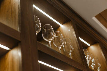 
Clean transparent wine glasses in a wooden cabinet. Empty wine glasses or cocktail glasses made of glass or crystal