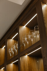 
Clean transparent wine glasses in a wooden cabinet. Empty wine glasses or cocktail glasses made of glass or crystal