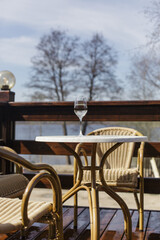 A glass of white wine on a white table on the terrace. Glare from a glass of wine and sunbeams
