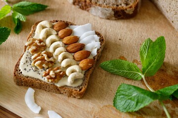Bread Slice with cashewbutter almonds, nuts, cocos on a wooden Table. High quality photo