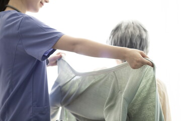 Nurse helping patient put on clothes