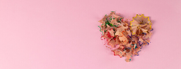 banner with colored heart-shaped pencil shavings on pink background. Decoration for St. Valentine's Day.