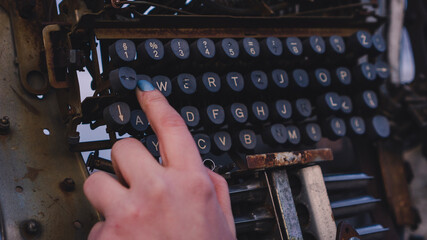 Woman's hand pressing buttons on the typewriter - obrazy, fototapety, plakaty