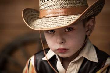 Portrait of a serious child. A small child dressed as a cowboy dreams of an adventure in the Wild West.