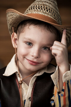 Happy child smiles. A portrait of a kid in a cowboy costume rejoices and dreams of adventure  in the Wild West.