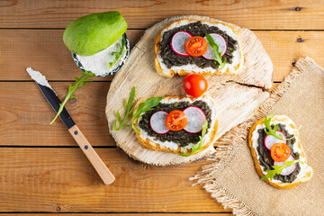 Healthy sandwiches with avocado, cream cheese and radish. Healthy toast with cream cheese, avocado, arugula and tomatoes on a rustic wooden table