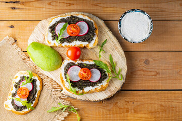 Healthy sandwiches with avocado, cream cheese and radish. Healthy toast with cream cheese, avocado, arugula and tomatoes on a rustic wooden table