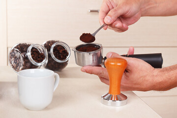 Barista pours ground coffee into the holder of coffee machine.