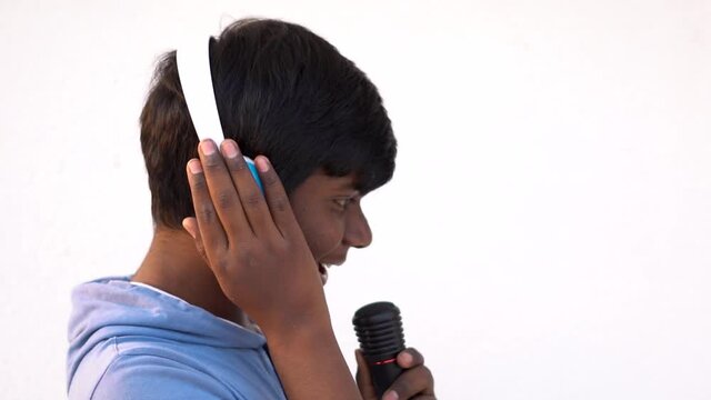 Indian Kid Wearing Headphones Singing While Holding The Mic