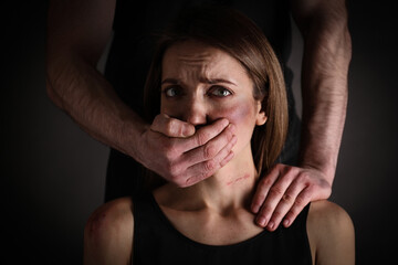 Man abusing scared woman on black background. Domestic violence