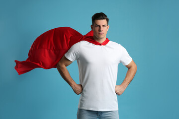 Man wearing superhero cape on light blue background
