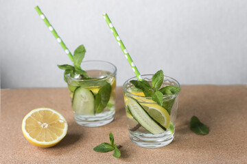 Two glasses with useful water from cucumber, lemon and mint for detoxification on a light...