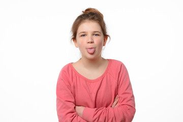 Portrait of offended young girl holding hands crossed and showing tongue, looking at camera