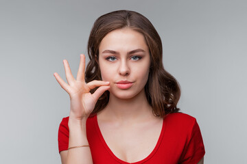 Your secrets safe with me concept. Young brunette woman showing zip gesture as if shutting mouth on...