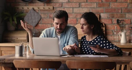 Focused young married couple calculating paper utility bills or managing budget, feeling stressed of data discrepancy in online e-banking system, worrying about money debt, financial problems concept. - Powered by Adobe