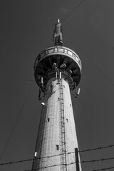 Bottom view of monumental concrete telecommunication tower under clear sky in sunlight. Vertical...