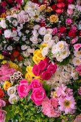 Many colorful artificial fake flowers background blooming beautiful.