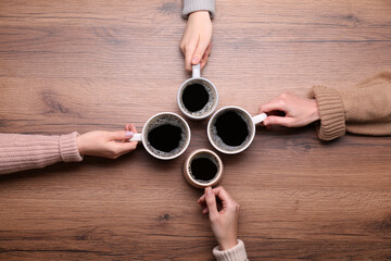 Women with cups of coffee at wooden table, top view