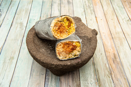 Male burrito with chipotle sauce on natural stone mortar