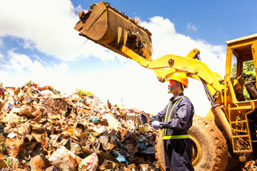 Engineer driving a loader in the recycling plant. Factory recycle workers are using a tablet to...