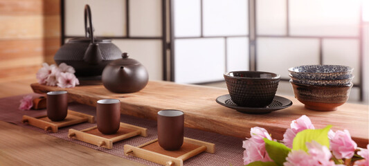 Beautiful set for traditional tea ceremony and sakura flowers on wooden table. Banner design