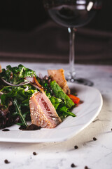 close-up fish salad with greens on a white plate