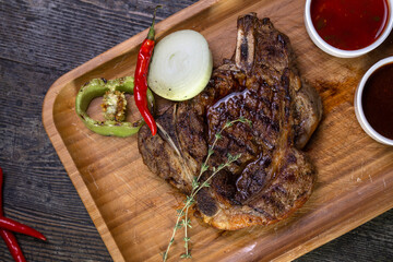 juicy beef steak with sauce and pepper on a wood board