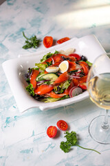 vegetable salad with salmon fillet in a white plate on a light background