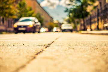 Clear day in the big city, the cars goes down the street. View from the level of asphalt