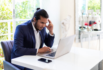 young latin entrepreneur dressed in a suit working on his laptop