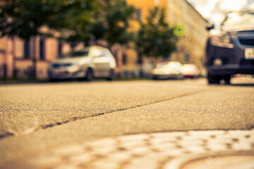 Clear day in the big city, a quiet street with trees and cars. View from the hatch on the pavement...