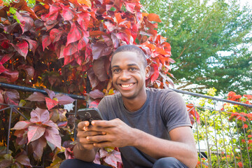 Excited african american millennial Young man hold smartphone feel euphoric reading good news,...