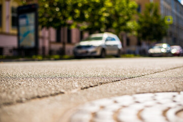 Clear day in the big city, a quiet street with trees and cars. View from the hatch on the pavement level