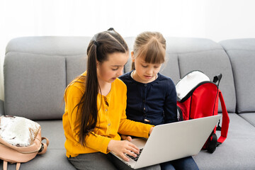 Two cute child girls using laptop together with fun and happiness