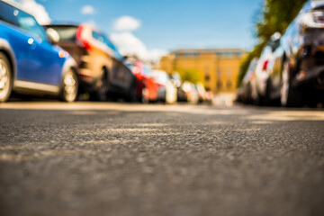 Obraz premium Clear day in the big city, a street with trees and parking cars. View from the level of asphalt
