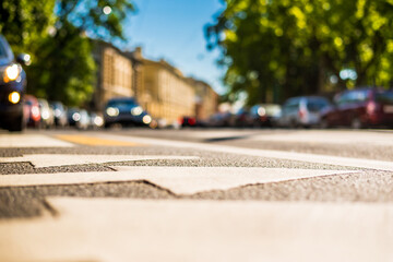 Clear day in the big city, a car rides through the streets near the park. View from the pedestrian crossing