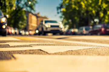 Clear day in the big city, a car rides through the streets near the park. View from the pedestrian crossing