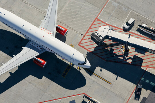 Aerial view of plane. Airplane in front of the passenger boarding bridge from airport terminal..