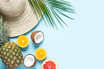 Women's hat with wide brim, tropical fruits and a branch of a palm tree on a blue background. Summer concept, vacation at sea. Banner. Flat lay, top view