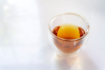 A glass of hot black tea on the white table.