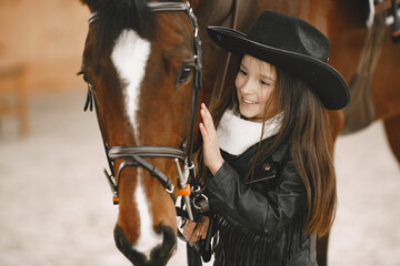 Fototapeta premium Little girl is riding a horse in a rancho