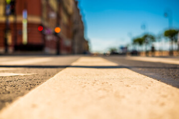 Clear day in the big city, a quiet street with trees and headlights of the approaching cars. View from the pedestrian crossing