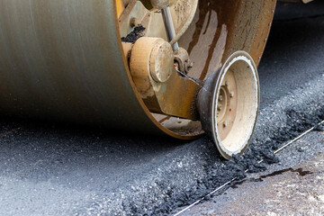 Asphalt paver on the road during asphalt compaction close up. Road repair. Laying a new road