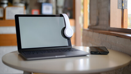 Mockup Laptop blank screen and headphone on screen, Laptop placed on a table in a cafe.