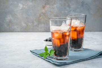Tea with berries and ice on a gray background. Side view, copy space.