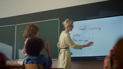 Teacher using interactive digital whiteboard. Student writing on smart board 