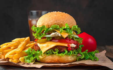 Burger, French fries and cola on a brown background. Side view, horizontal.