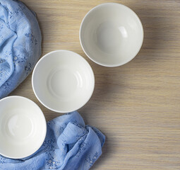 White clean empty plates on a wooden table with a blue napkin. Top view.