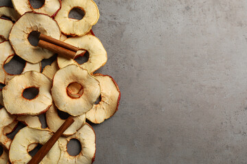 Delicious apple chips and cinnamon on grey table, flat lay. Space for text