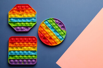 Rainbow pop it fidget toys on color background, flat lay. Space for text - obrazy, fototapety, plakaty